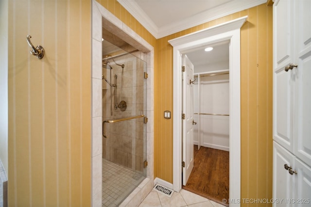 bathroom featuring tile patterned flooring, a shower stall, and crown molding