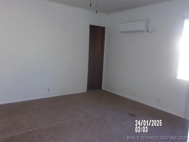 unfurnished room with carpet, baseboards, and a wall mounted AC