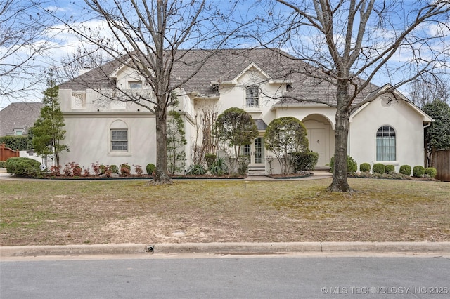 french country style house with stucco siding, french doors, and a front lawn