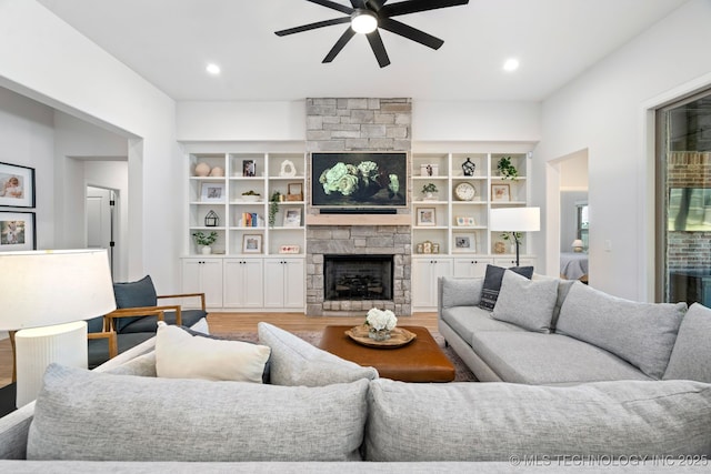 living area featuring recessed lighting, a stone fireplace, light wood-style flooring, and ceiling fan