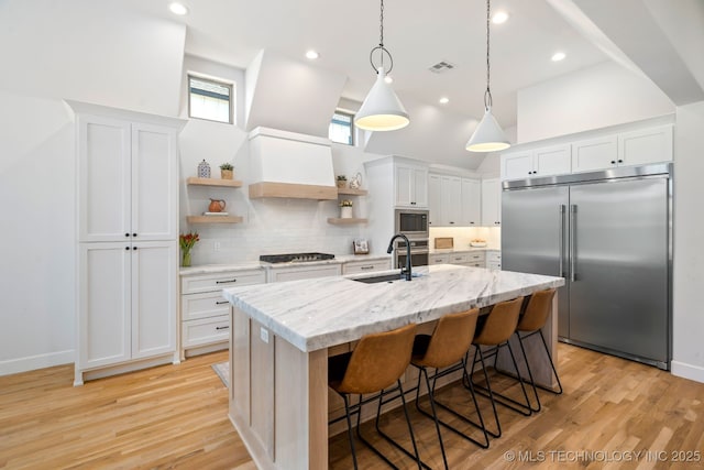 kitchen featuring visible vents, a sink, built in appliances, a towering ceiling, and open shelves