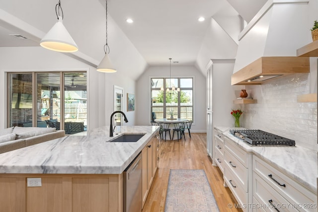 kitchen with light wood finished floors, vaulted ceiling, island exhaust hood, stainless steel appliances, and a sink