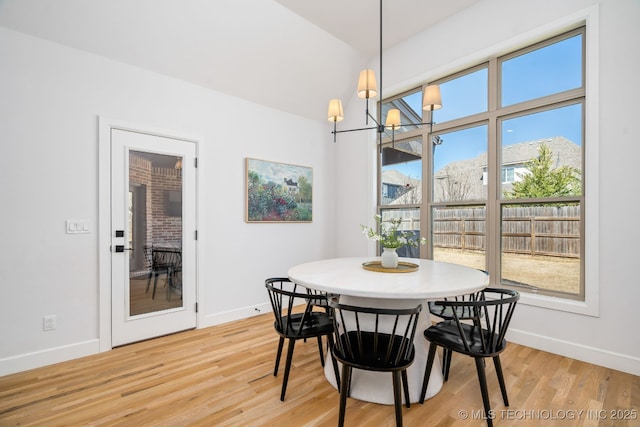 dining area with light wood finished floors, an inviting chandelier, and baseboards