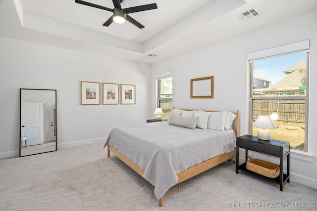 bedroom with carpet, baseboards, visible vents, ceiling fan, and a raised ceiling