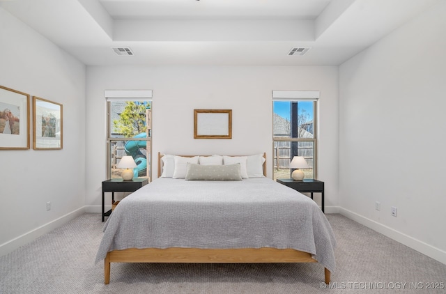 bedroom featuring a tray ceiling, multiple windows, and visible vents