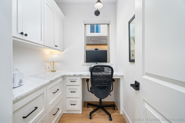 home office featuring light wood finished floors and built in study area