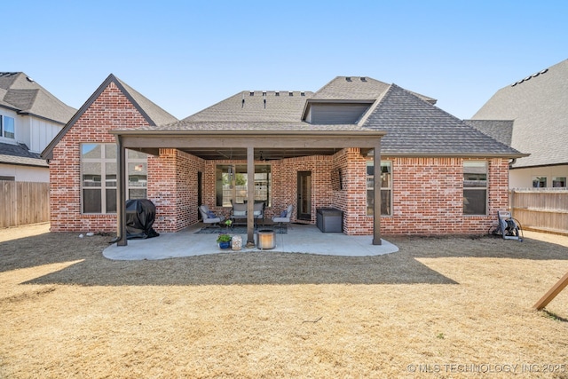 rear view of property featuring a patio, a fenced backyard, brick siding, and roof with shingles