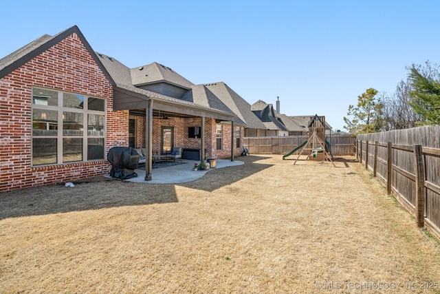 view of yard featuring a patio, a fenced backyard, and a playground