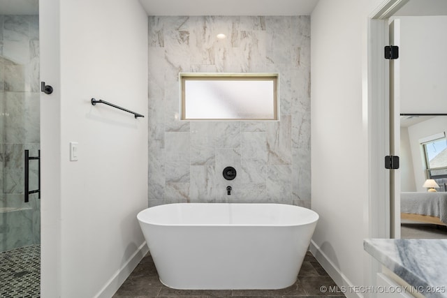 bathroom featuring a shower stall, baseboards, and a freestanding tub