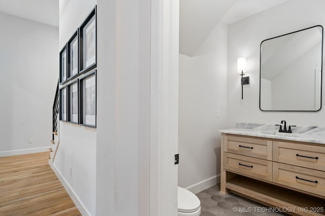 bathroom featuring vanity, toilet, wood finished floors, and baseboards