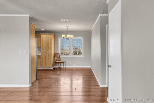 dining space featuring wood finished floors, baseboards, visible vents, an inviting chandelier, and ornamental molding