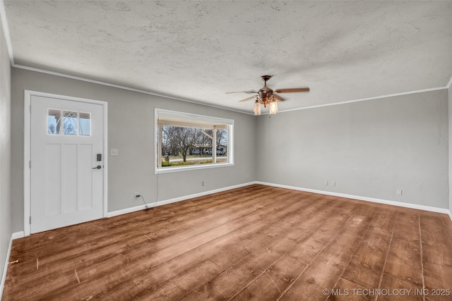 entryway featuring a ceiling fan, wood finished floors, baseboards, ornamental molding, and a textured ceiling