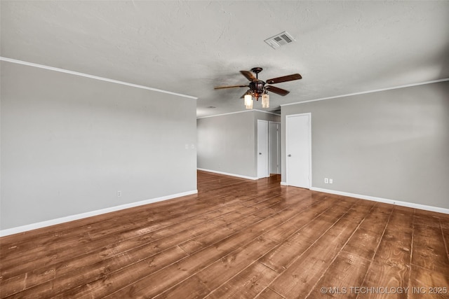 empty room featuring wood finished floors, baseboards, visible vents, ceiling fan, and ornamental molding