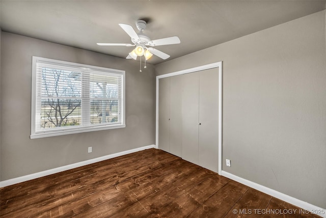 unfurnished bedroom featuring dark wood-type flooring, baseboards, a closet, and ceiling fan