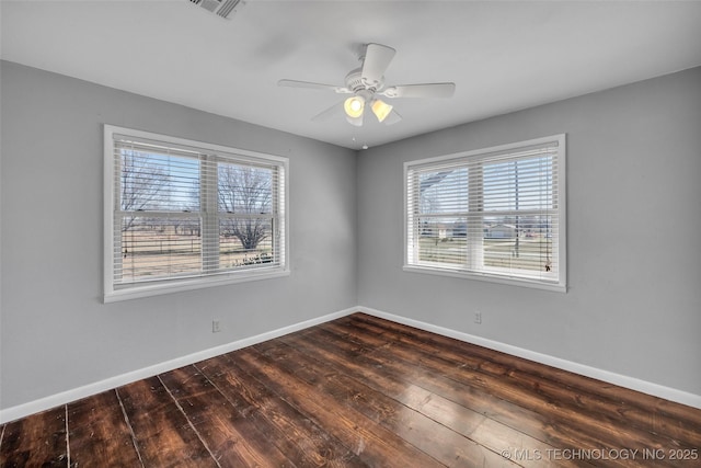 unfurnished room featuring a wealth of natural light, baseboards, and dark wood-style floors