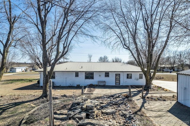 view of front of home with brick siding, metal roof, and a patio