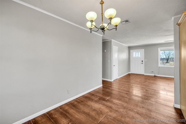 interior space with hardwood / wood-style floors, baseboards, visible vents, ornamental molding, and a notable chandelier