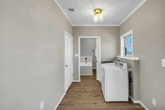 laundry area featuring visible vents, ornamental molding, wood finished floors, separate washer and dryer, and laundry area