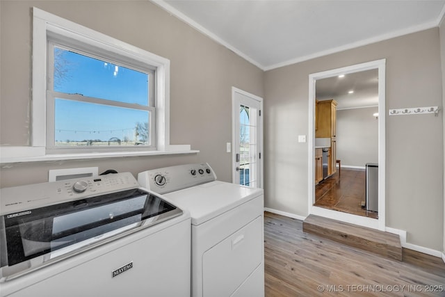 laundry area featuring independent washer and dryer, ornamental molding, wood finished floors, baseboards, and laundry area