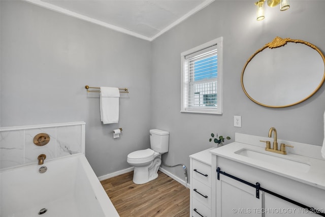 bathroom with vanity, wood finished floors, baseboards, a tub, and toilet