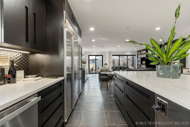 kitchen with dark tile patterned flooring, recessed lighting, light countertops, appliances with stainless steel finishes, and tasteful backsplash