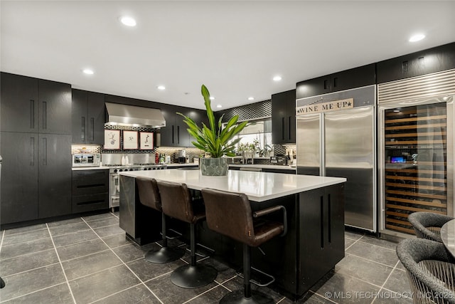 2440 E 47th Pl, Tulsa, OK 74105 - kitchen with wall chimney range hood, premium appliances, beverage cooler, a kitchen island, and backsplash