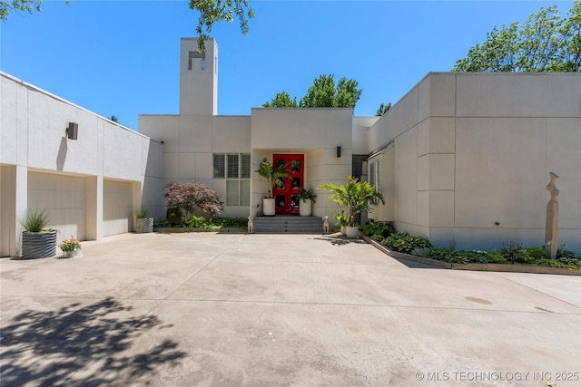 2440 E 47th Pl, Tulsa, OK 74105 - contemporary home with a garage, driveway, stucco siding, and a chimney