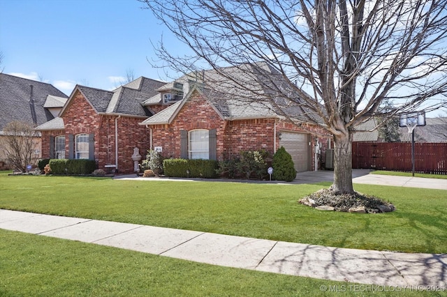 view of front of home featuring a front yard, brick siding, an attached garage, and fence