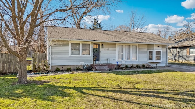 view of front of home featuring a shingled roof, a front lawn, and fence