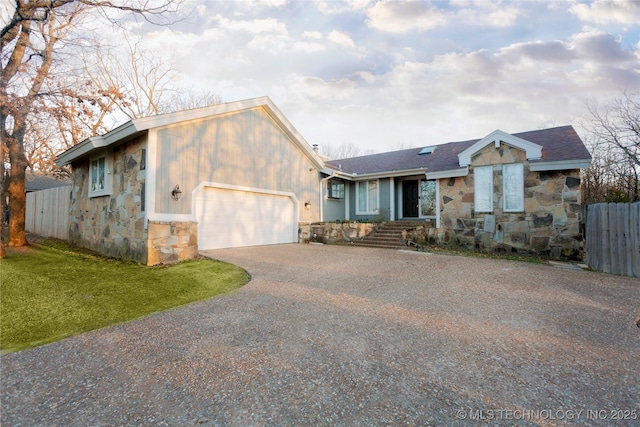 view of front facade featuring an attached garage, a front lawn, fence, stone siding, and driveway