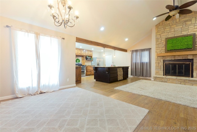 kitchen with light wood-type flooring, range with two ovens, a stone fireplace, white refrigerator with ice dispenser, and open floor plan