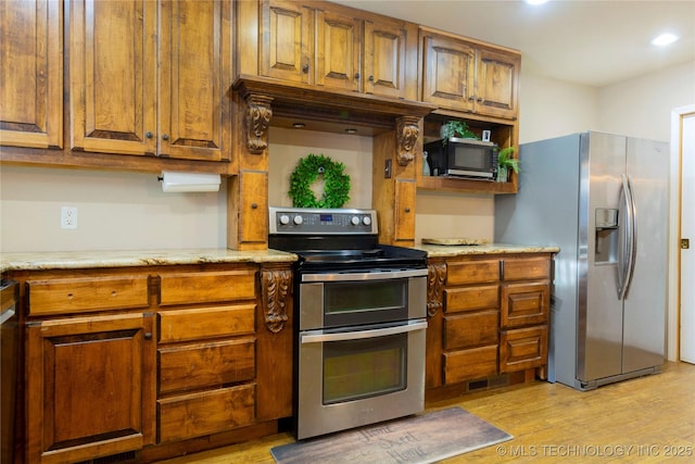 kitchen with brown cabinetry, visible vents, appliances with stainless steel finishes, and light wood-type flooring