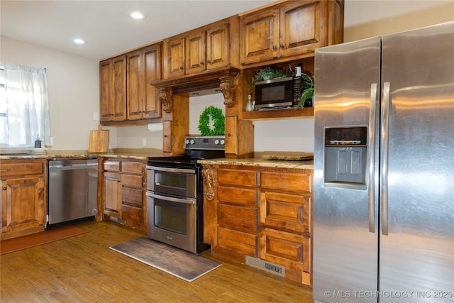 kitchen featuring visible vents, recessed lighting, brown cabinets, wood finished floors, and stainless steel appliances