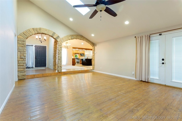 unfurnished living room with ceiling fan with notable chandelier, recessed lighting, wood finished floors, and baseboards