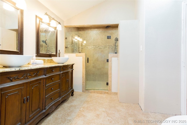 full bathroom featuring lofted ceiling, double vanity, a stall shower, and a sink