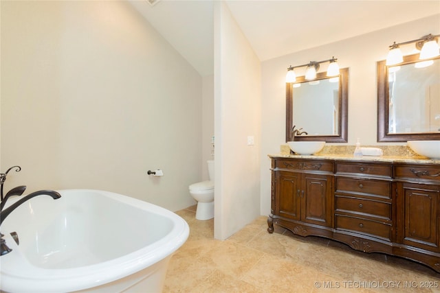 bathroom featuring a sink, a freestanding tub, toilet, and double vanity