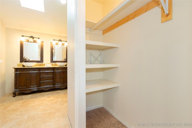 full bathroom with a sink, baseboards, and double vanity