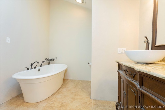 full bathroom featuring tile patterned floors, a freestanding tub, and vanity