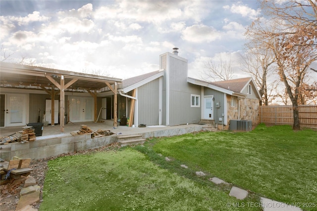 back of property with cooling unit, fence, a yard, a chimney, and a patio area