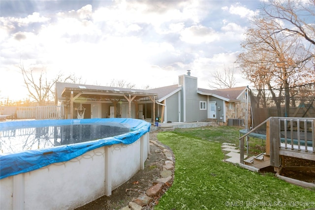 exterior space with a fenced in pool, fence, a lawn, cooling unit, and a chimney