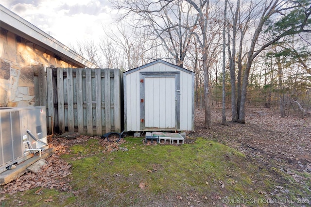 view of shed with cooling unit and fence