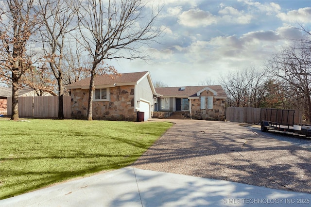 view of front of property featuring an attached garage, fence, a front yard, stone siding, and driveway