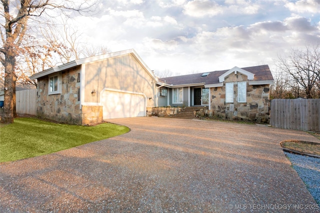 view of front of home with aphalt driveway, stone siding, a garage, and fence