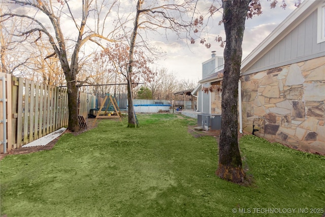 view of yard with cooling unit, a fenced in pool, and a fenced backyard