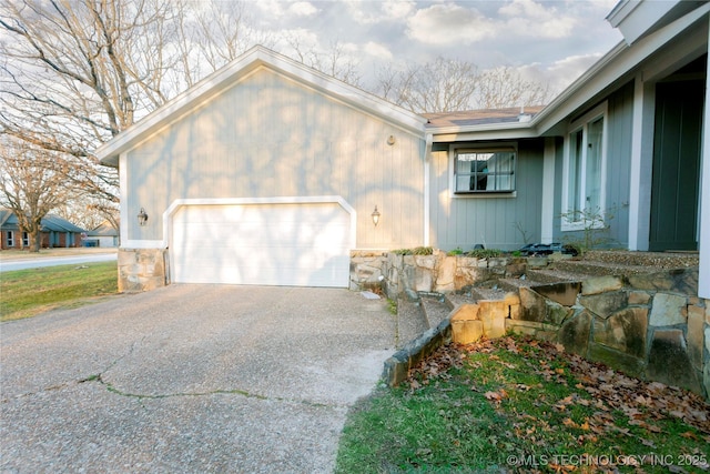 view of front of house featuring stone siding, driveway, and a garage