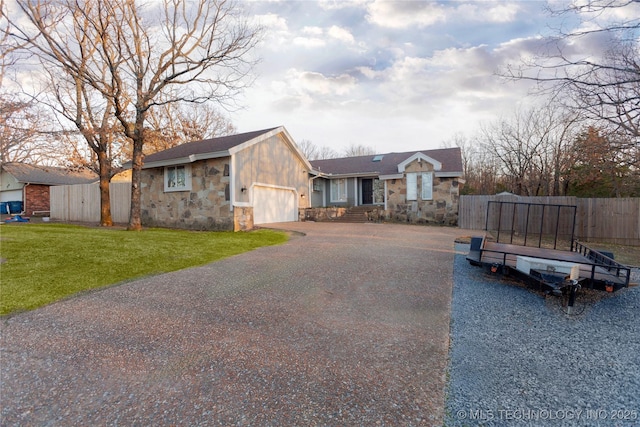 view of front of home with aphalt driveway, stone siding, fence, a front yard, and an attached garage