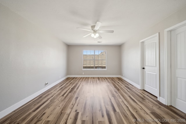 spare room with visible vents, wood finished floors, baseboards, and ceiling fan