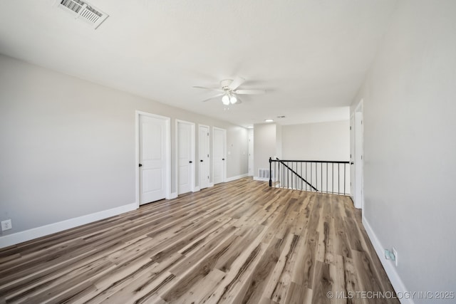 empty room featuring visible vents, baseboards, wood finished floors, and a ceiling fan