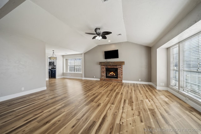 unfurnished living room with a brick fireplace, baseboards, light wood-style floors, and vaulted ceiling