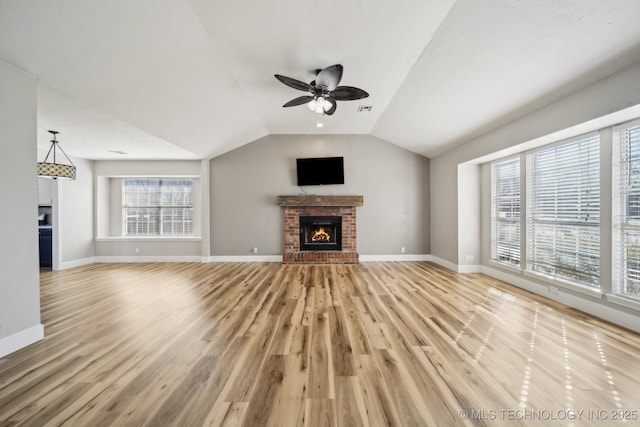 unfurnished living room featuring light wood finished floors, a brick fireplace, baseboards, vaulted ceiling, and a ceiling fan